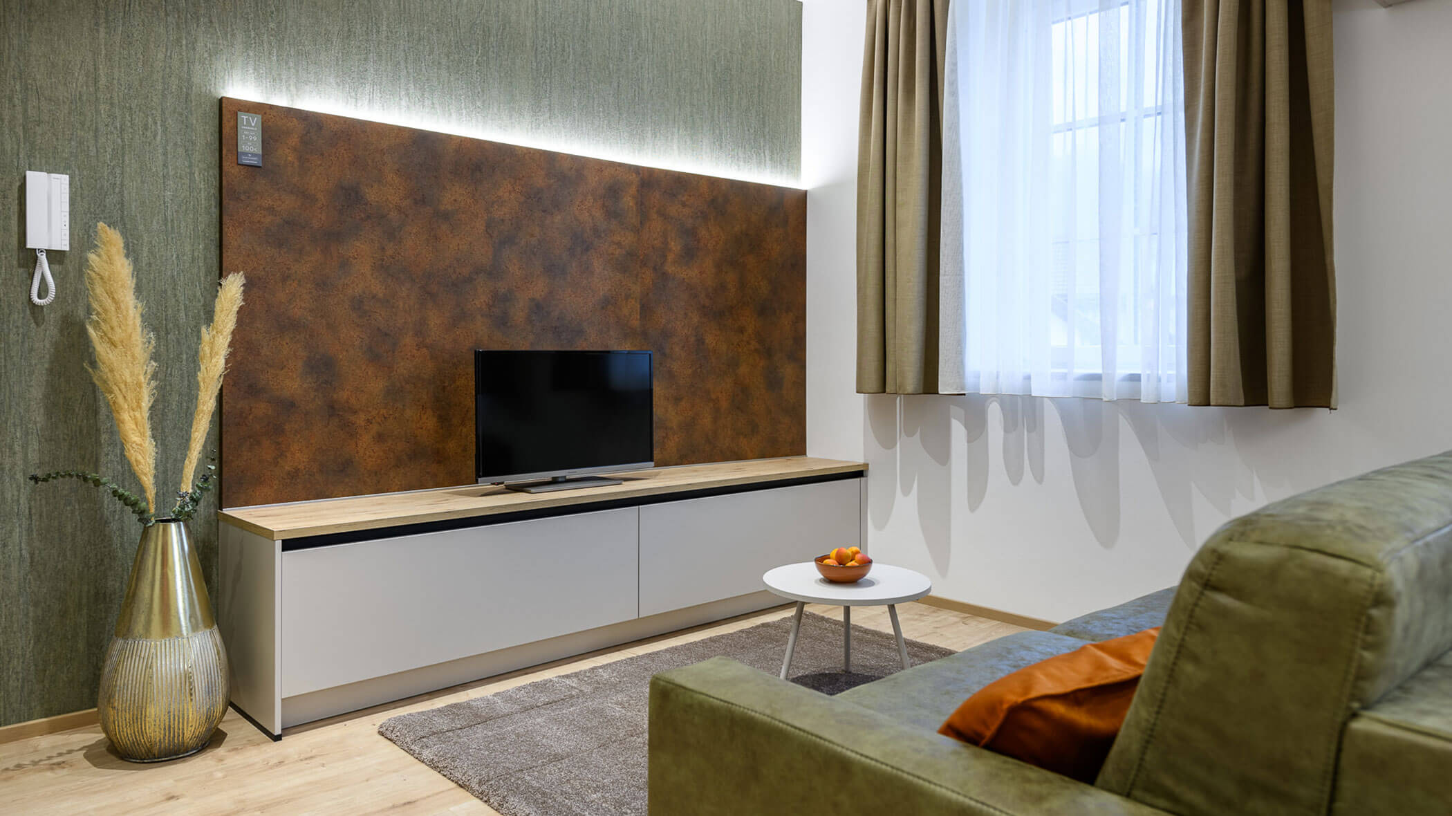 Soggiorno con divano verde nell'appartamento di Villa Fauster